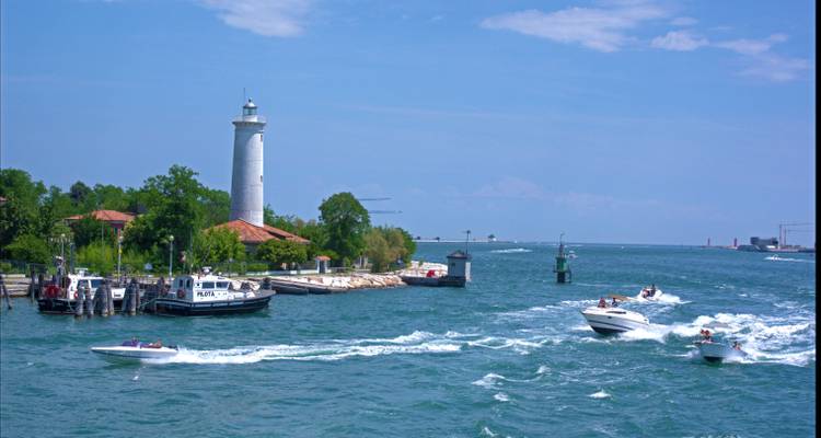 Küstenszene mit einem Leuchtturm und Booten auf dem Wasser.