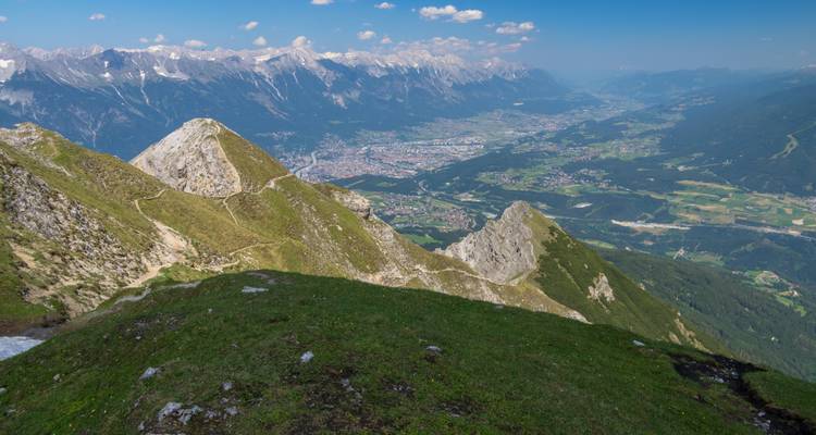 Panoramablick vom hochalpinen Gebirgskamm über die Talstadt und die umschließenden Berge.