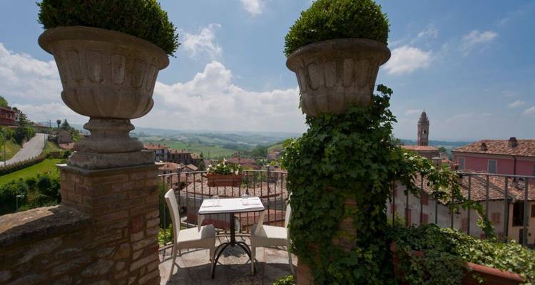 Vue panoramique depuis une terrasse sur le toit avec des montagnes et une église au loin.