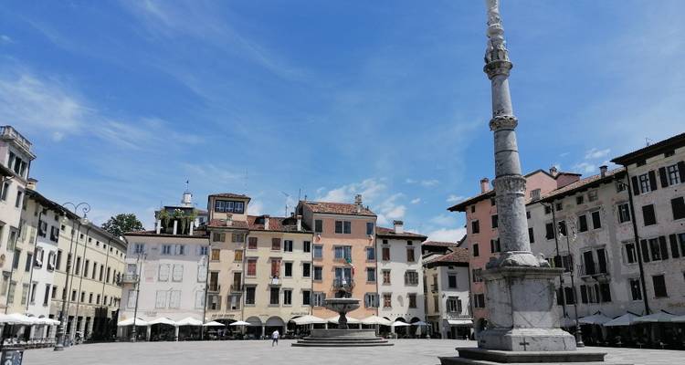 Groot open plein met historische architectuur en een zuil met standbeeld.