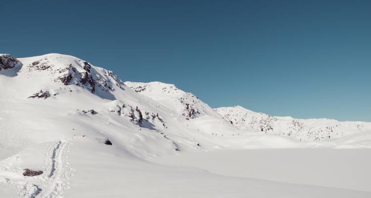 Paysage de montagne enneigée avec un ciel bleu clair.
