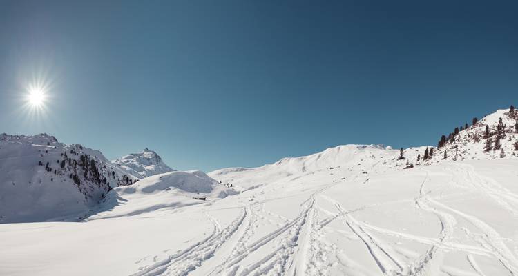 Vue panoramique de montagnes enneigées sous un soleil éclatant.