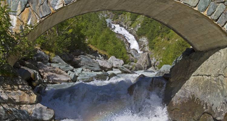 Waterval onder een brug in een bergachtige omgeving.