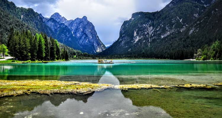 Lac calme entouré de montagnes et de forêt.