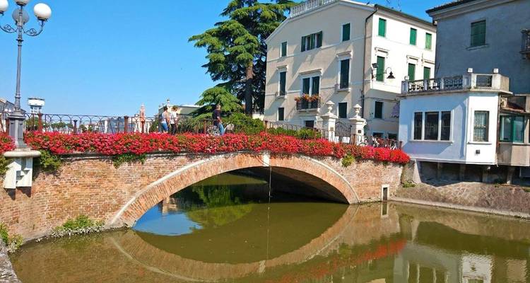 Steinbrücke mit Blumenschmuck und Kanalblick.