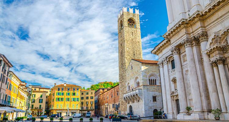 Stadsplein met een toren en kleurrijke gebouwen onder een blauwe hemel.