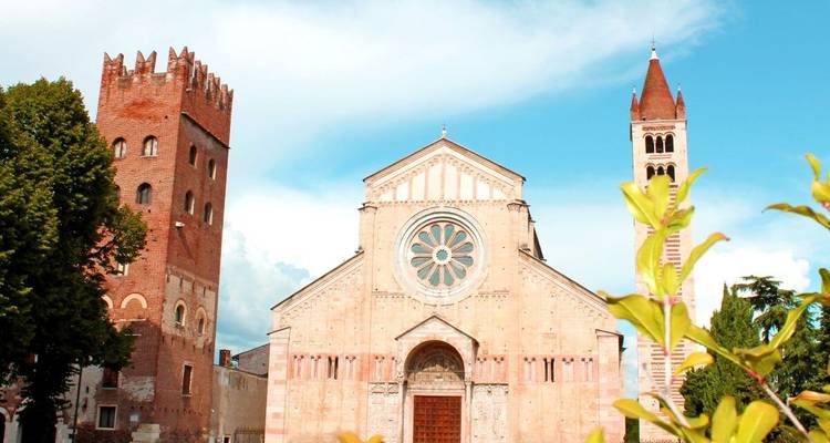 Tours et façade d'une église historique avec verdure et ciel bleu.