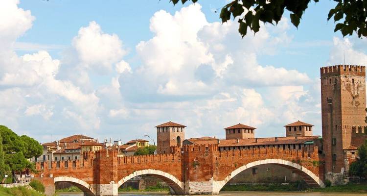 Pont historique en brique au-dessus d'une rivière avec des bâtiments de la ville derrière.