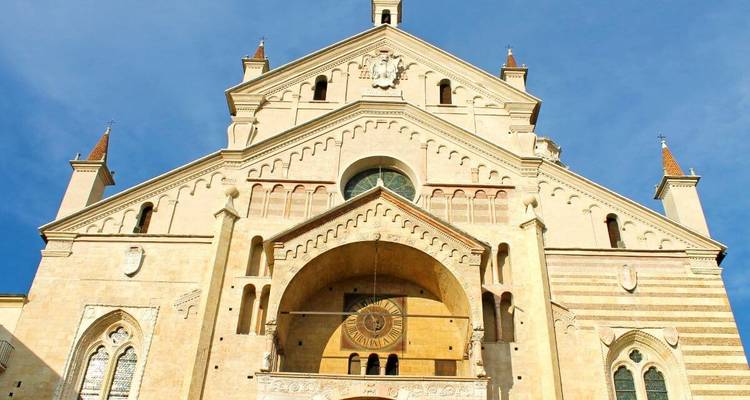 Façade d'une cathédrale historique avec des détails architecturaux sur un ciel bleu.