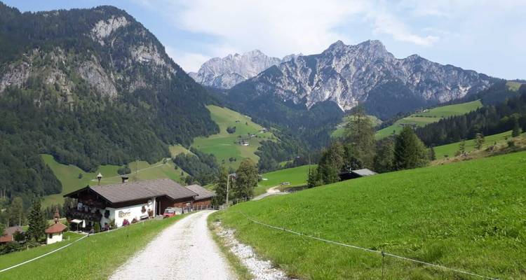 Route de montagne menant à un paysage alpin pittoresque avec des maisons.