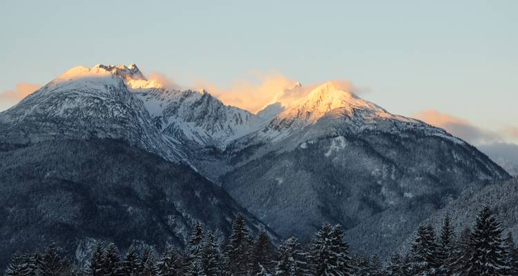 Montagnes enneigées sous une douce lueur de coucher de soleil.