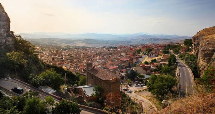 Stadt eingebettet in hügelige Landschaft mit gewundenen Straßen.