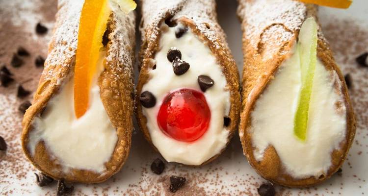 Drei sizilianische Cannoli mit Cremefüllung und Garnitur.