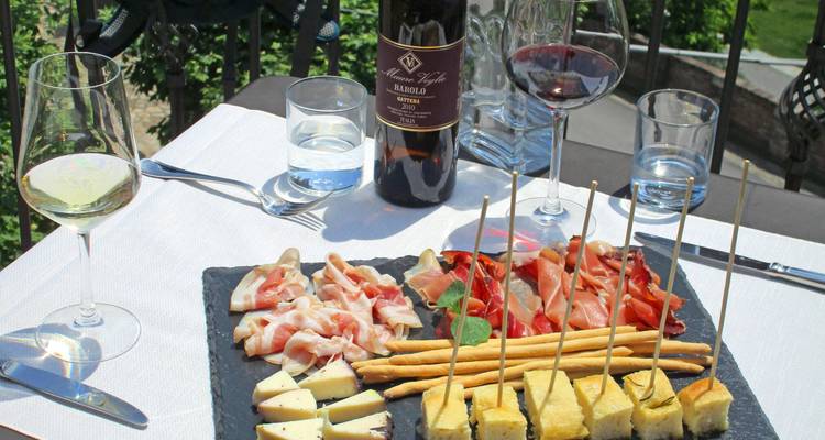 Table d'extérieur dressée avec des fromages locaux, de la charcuterie, des gressins et du vin rouge et blanc.
