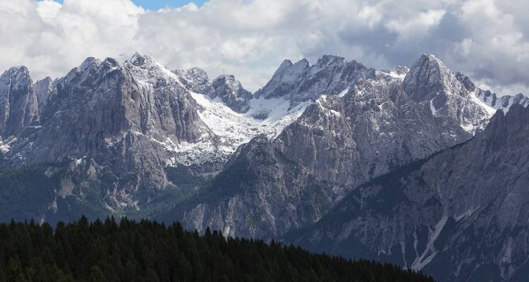 Sommets de montagnes enneigés sous un ciel nuageux.