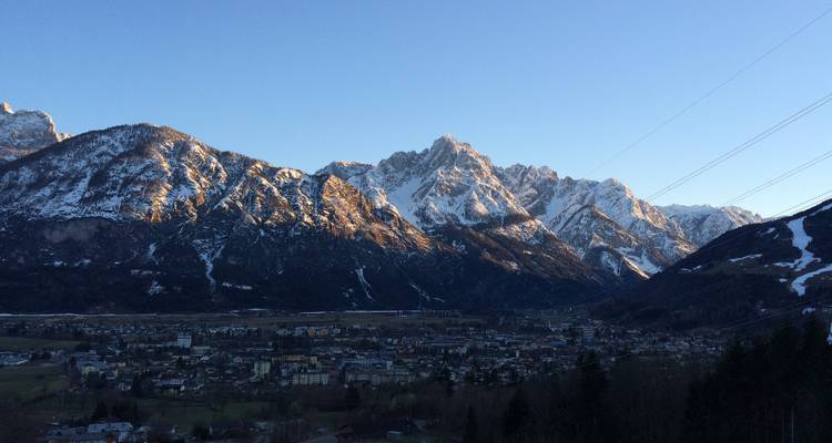 Petite ville sous des montagnes enneigées au coucher du soleil.