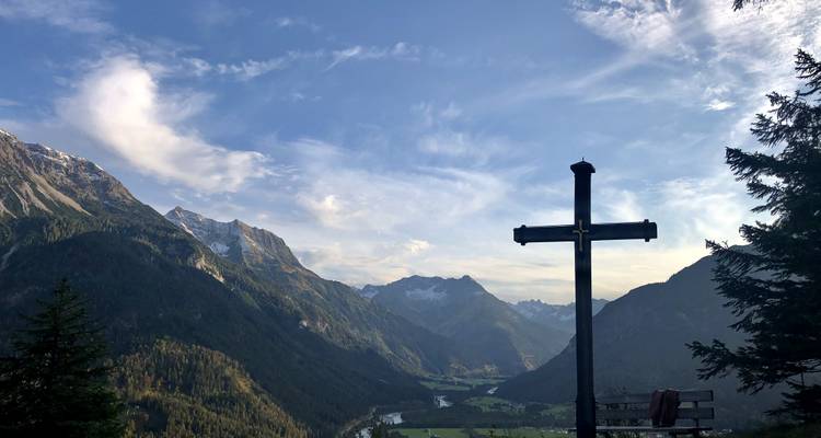 Croix sur une montagne surplombant une vallée.