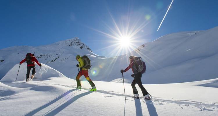 Des skieurs sur une montagne enneigée ensoleillée avec un vif éclat de soleil.