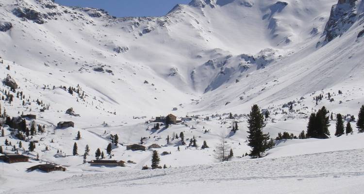Un paysage alpin enneigé avec des chalets éparpillés.