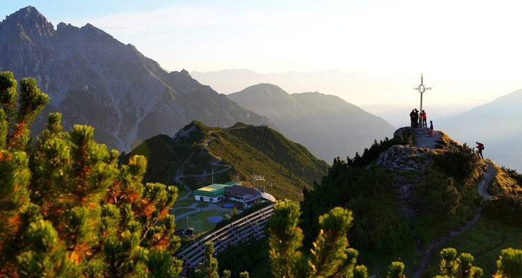 Groupe de personnes et une croix sur un sommet de montagne avec vues panoramiques.