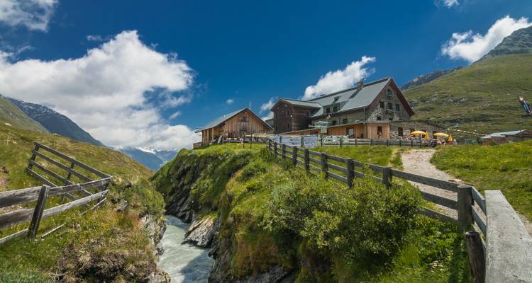 Berghütte neben einem Fluss mit einem Holzzaun.