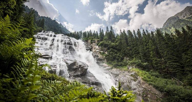 Belle cascade dans une zone montagneuse boisée.