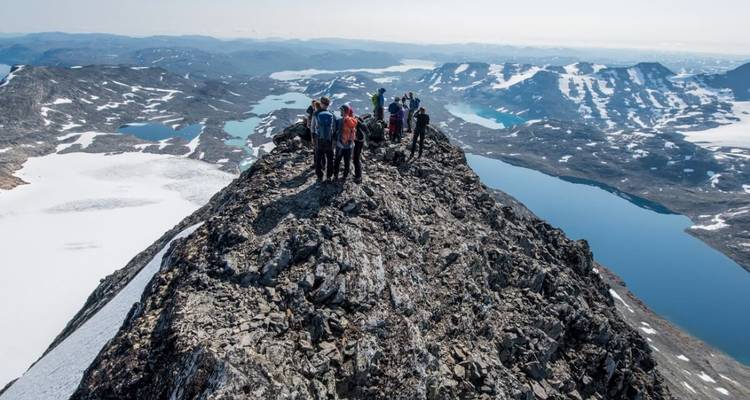 Group hiking on a mountain ridge with snowy peaks.