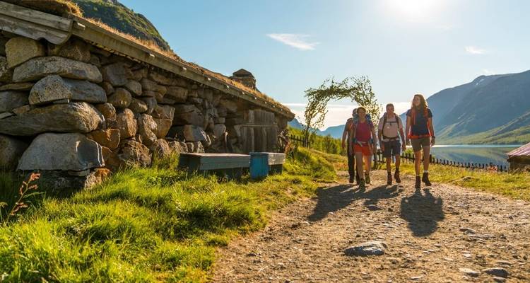 Hikers walking along a path next to a wooden structure.