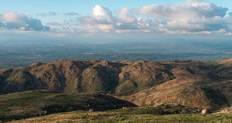 Vue panoramique de collines ondulantes sous un ciel nuageux.