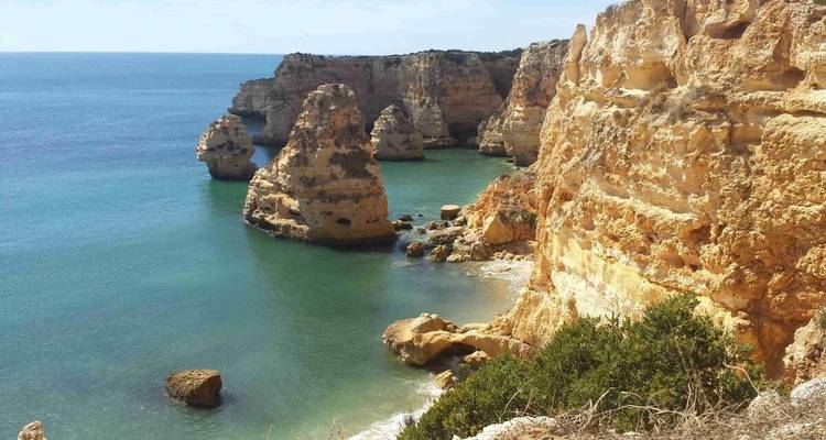 Hautes formations rocheuses le long d'une mer bleue claire.