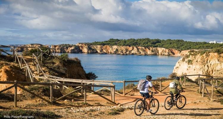 Deux cyclistes sur un sentier avec vue sur mer.