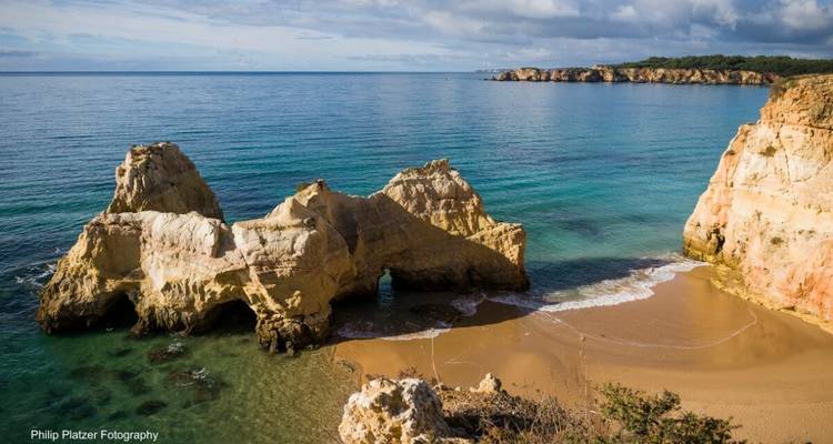 Plage avec formations rocheuses et eau bleu clair.
