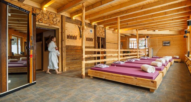 Intérieur d'un chalet confortable avec un mobilier en bois et une personne qui marche.