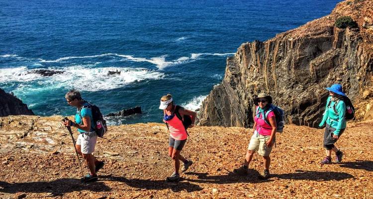 Groupe en randonnée le long d'un sentier côtier rocheux.