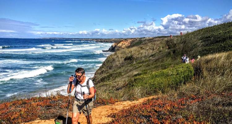 Randonneurs sur un sentier de falaise surplombant l'océan.
