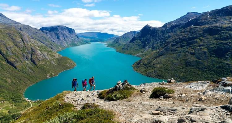 Group hiking with a panoramic view of turquoise lake and mountains.