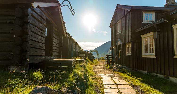 Traditional wooden houses with a stone path leading to mountains.