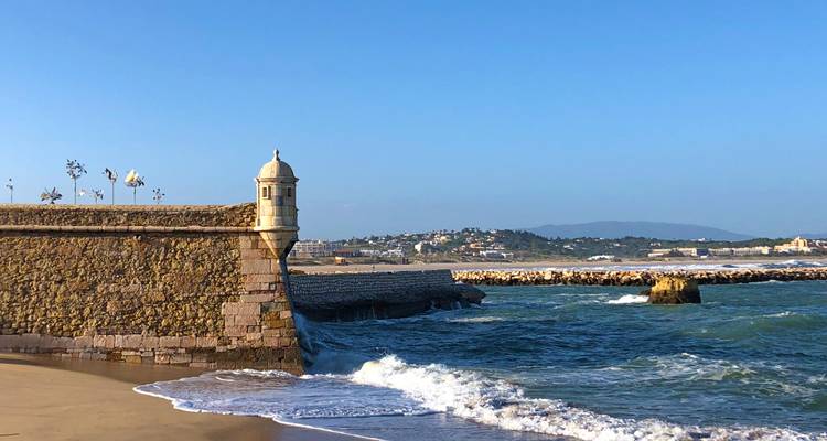 Murs de fort en pierre au bord de la mer avec une vue lointaine de la ville.