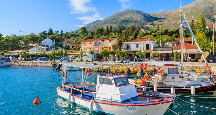 Colorful boats in a vibrant harbor with mountains in the background.