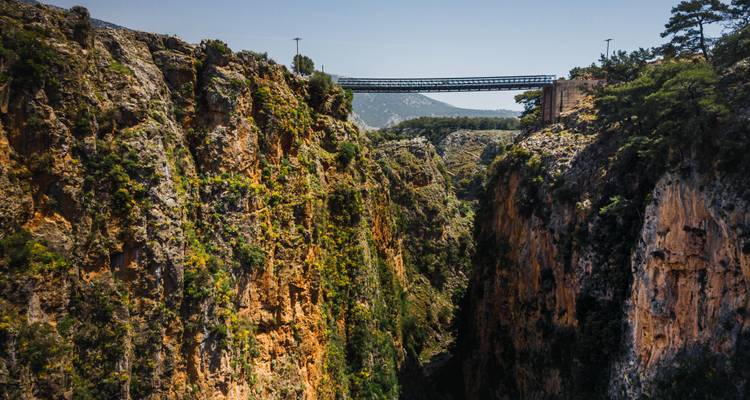 Steel bridge over a rugged canyon viewed from above.