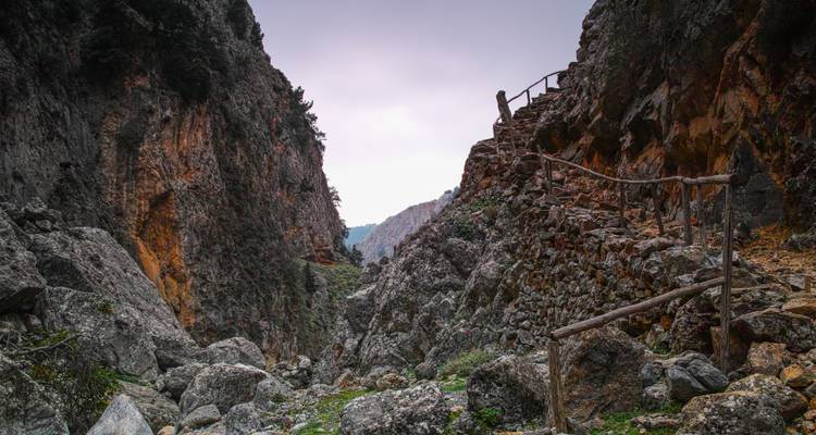 Mountain pass with rocky terrain and a wooden fence.