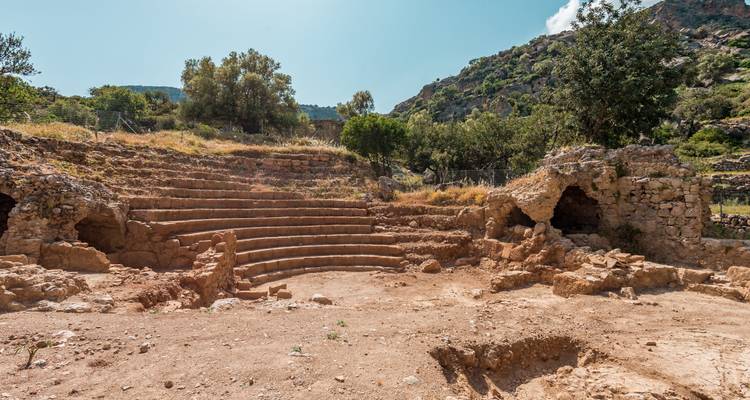 Ancient ruins and amphitheater with mountainous background.