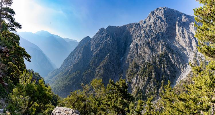 Dramatic mountain range with lush forests under a clear sky.