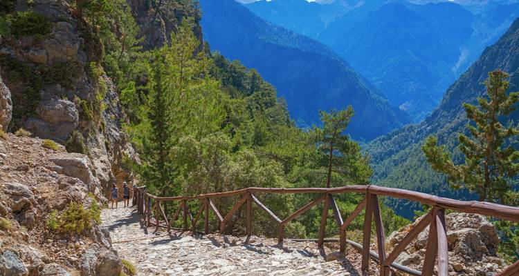Hikers on a steep trail in a mountainous gorge.