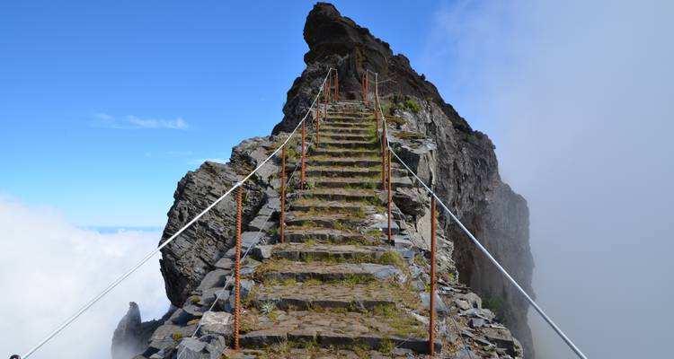 Escalier de pierre escarpé grimpant vers un sommet à travers les nuages.