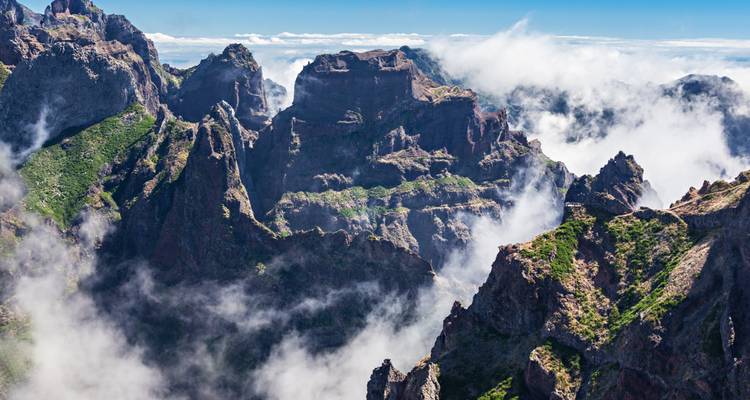 Vue aérienne de pics montagneux escarpés enveloppés dans les nuages.