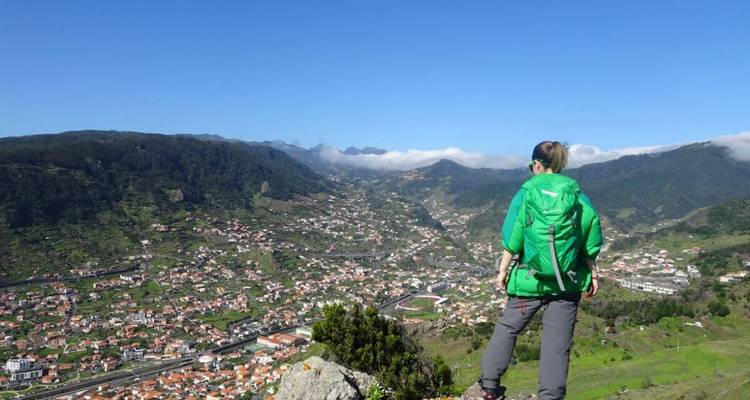 Person overlooking a valley with mountains.