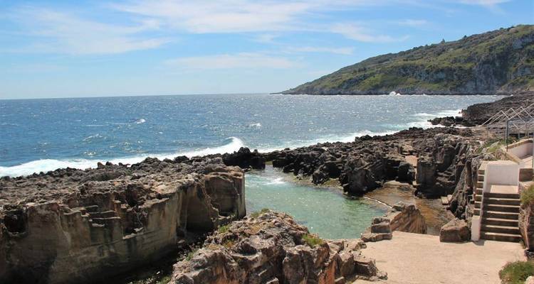 Zone côtière rocheuse avec mer bleue claire et vagues.