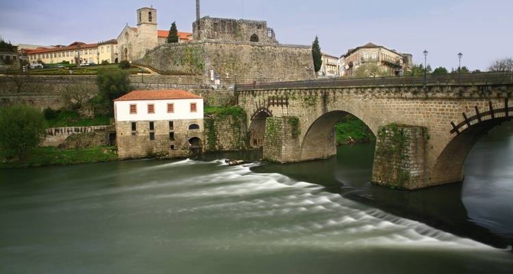 Ville historique avec pont de pierre et eau courante.