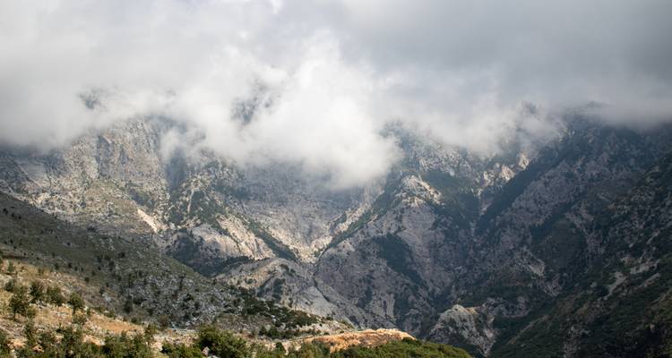 Bergige Landschaft mit Wolken, die die Gipfel teilweise bedecken.